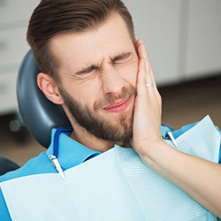 A young man holding his mouth in pain.