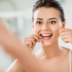 young woman flossing her teeth 