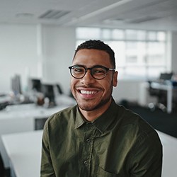 smiling person sitting on a desk at their office