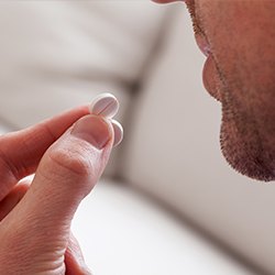 Hand holding a white antibiotic tablet pill