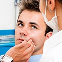 Male patient in dental chair holding cheek in pain