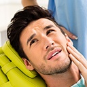 Older male dental patient holding cheek