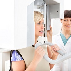 A dentist helping a patient receive a cone beam scan.