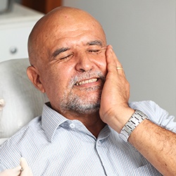 Man in dental chair holding jaw