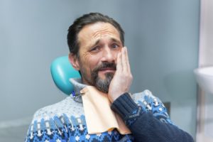 Worried man with beard sitting in dentist’s chair needing root canal