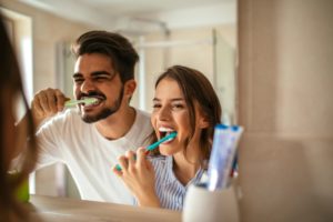 Couple brushing their teeth to avoid seeing an emergency dentist in Pearland 