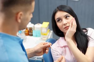 woman with painful dental emergency talking to her dentist 