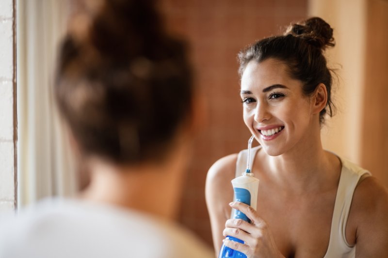 girl water flossing in mirror